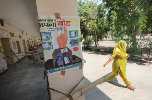 Mulher passa em frente de um cartaz eleitoral na Índia.