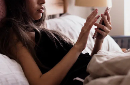 Mulher deitada na cama ao telemóvel
