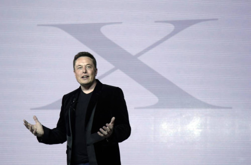 Elon Musk fala com o símbolo do X por detrás