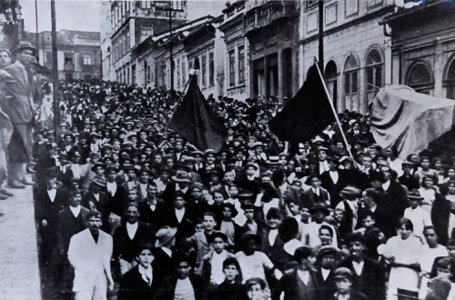 Imagens de uma das ruas de São Paulo tomada de trabalhadores com bandeiras vermelhas na greve geral de 1917. 
