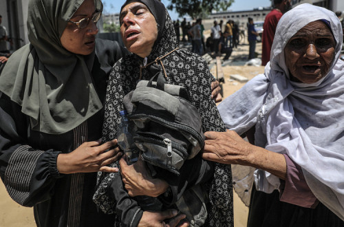 Uma mãe palestiniana chora abraçada à mochila do filho, morto por soldados israelitas quando tentava buscar comida no ponto de ajuda humanitária de Zikim.
