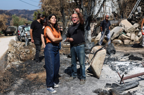 A coordenadora do Bloco de Esquerda (BE), Mariana Mortágua (E), conversa com o agricultor Hélder Correia (D), durante a visita às zonas afetadas pelos incêndios, que já tinham sido afetadas pelos incêndios em 2017 e voltou a ver as suas terras destruídas pelo fogo, em Avô, Oliveira do Hospital, 25 de agosto de 2025.