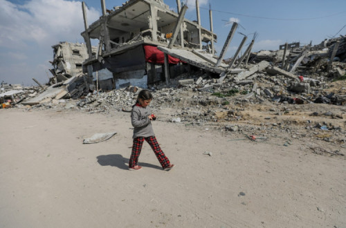 Menina passeia junto a edifícios destruídos no campo de refugiados de Jabalya, no norte da Faixa de Gaza