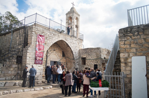 Pessoas reunidas perto da entrada da igreja no mercado de Natal em Bir'im, em 13 de dezembro de 2025.