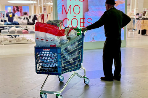 homem com carrinho de supermercado num centro comercial