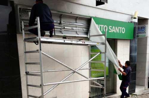 Trabalhador remove o nome do BES de uma agência, para afixar depois o do Novo Banco