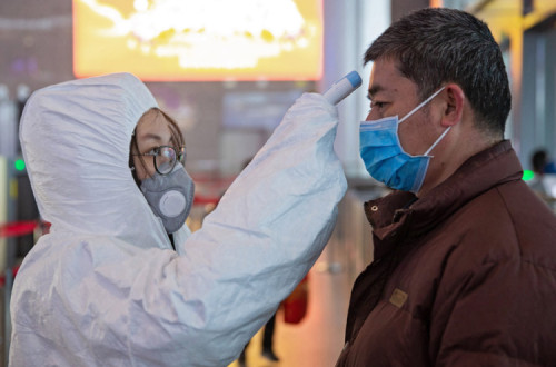 Equipas médicas tiram a temperatura aos passageiros na estação ferroviária de Nanjing, China. 