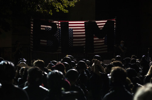 Manifestantes à porta do edifício federal onde tem havido confrontos com os agentes enviados por Trump. Foto de ETIENNE LAURENT/EPA/Lusa.