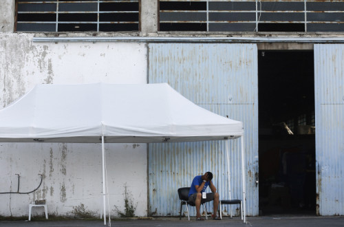 Sobrevivente do naufrágio à porta do armazém para onde foram levados. Foto de YANNIS KOLESIDIS/EPA/Lusa.