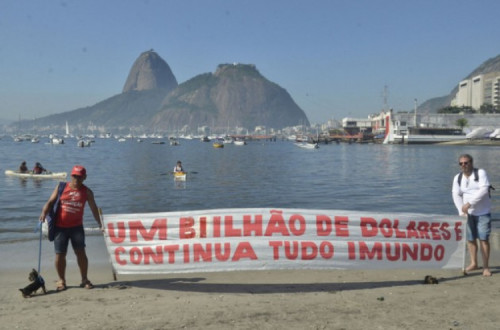 “Um bilhão de dólares e tudo continua imundo”, diz uma faixa na praia da baía de Guanabara, no Rio de Janeiro, onde acontecerão várias competições náuticas dos Jogos Olímpicos e cuja descontaminação é uma promessa não cumprida. Foto: Fernando Frazão/Agência Brasil