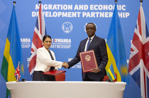 Priti Patel, secretária de Estado do Interior britânica com Vincent Biruta, ministro dos Negócios Estrangeiros do Ruanda no ato de assinatura do acordo. Abril de 2022. Foto de EUGENE UWIMANA/EPA.
