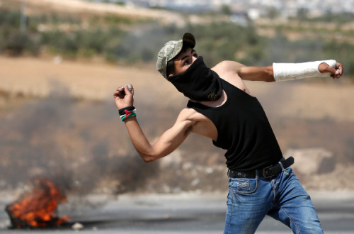 Jovem palestiniano responde à pedrada aos ataques a tiro das forças armadas de Israel – Foto de Abed Al Hashlamoun/Epa/Lusa