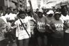 Manifestação de pessoas HIV positivas na Cidade do Cabo em 2002, no âmbito da Treatment Action Campaign que defrontou Thabo Mbeki o presidente negacionista da SIDA. Foto de Louis Reynolds/Flickr.