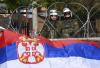 Soldados da Nato em frente a uma bandeira sérvia. Foto de GEORGI LICOVSKI/EPA/Lusa.
