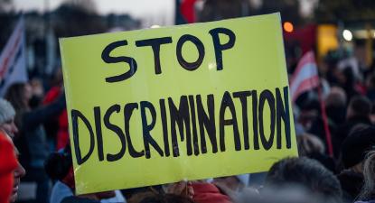 Cartaz amarelo onde se lê: "Stop Discrimination"