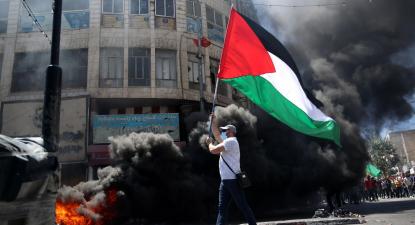 Manifestante palestiniano em Hebron com uma bandeira da Palestina na mão.