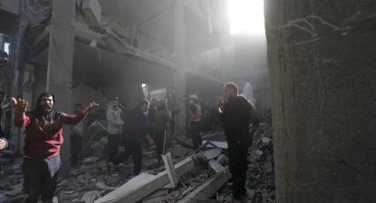 Palestinianos procuram corpos e sobreviventes nos escombros de um edifício residencial destruído por um ataque aéreo israelita, no campo de refugiados de Khan Younis, no sul da Faixa de Gaza,
